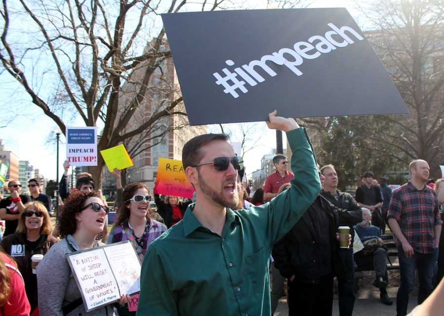 Protester marches with crowd as they chant to impeach President Donald Trump.