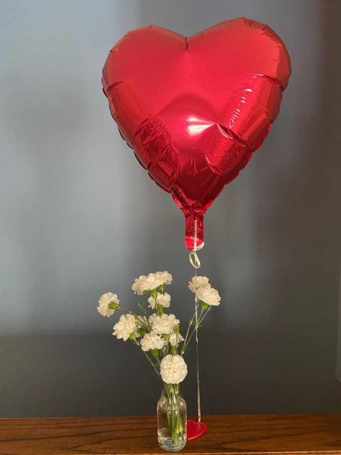 ballon that is shaped like a heart and flowers on a table
